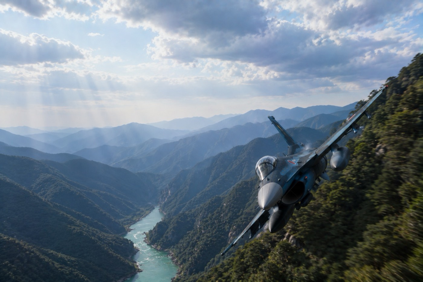 緑の峡谷を、川筋に沿って低空でバンクする F-2
